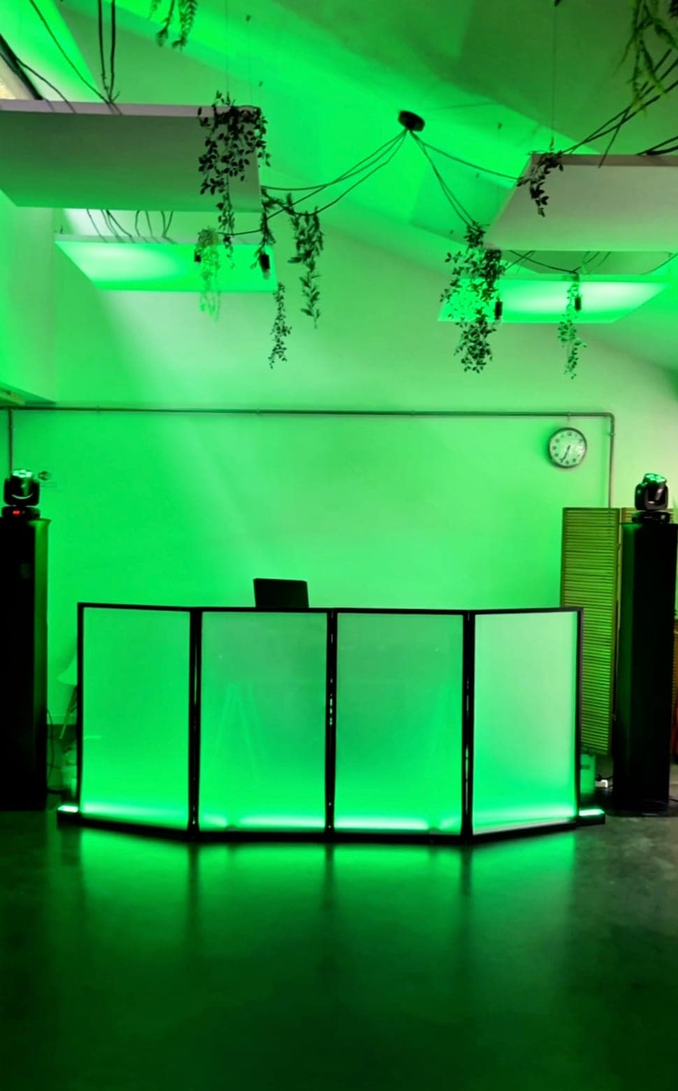 Régie DJ avec façade lumineuse, lyres et enceintes, sous un éclairage vert